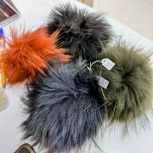 porte clés en forme de boule et de poiles, de couleur noir, orange, gris, posé sur une table