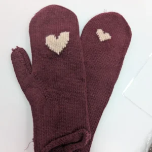 gants de couleur bordeaux avec un cœur beige, posé sur une table
