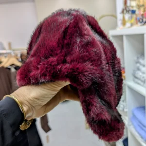 casquette en fourrure de couleur bordeaux, porté par une main