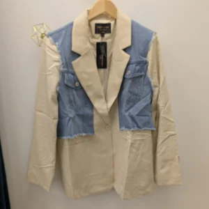 veste blazer de couleur beige et bleu, portée par un cintre